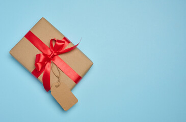 The box is wrapped with red ribbon and brown craft paper with a tag on a blue background