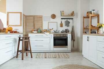 Interior of light kitchen with autumn decor, pumpkins and counters