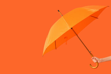 Female hand with orange umbrella on orange background © Pixel-Shot