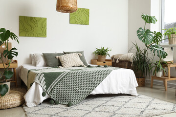 Stylish bedroom with comfortable bed and houseplants