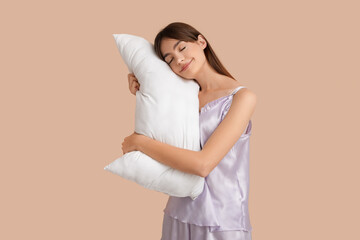 Beautiful young woman leaning on pillow on beige background