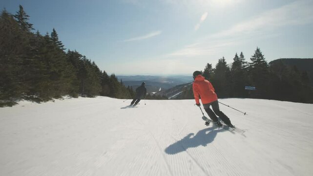 4K video of a couple man and woman skiers alpine skiing on cold winter snow at a ski resort mountain with sunshine. Adventure and thrill while on vacation and holiday. Killington, Vermont, USA. - Powered by Adobe
