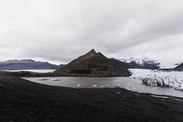 Icebergs floating in a glacial lake with a black sand beach and a mountain in the background in iceland