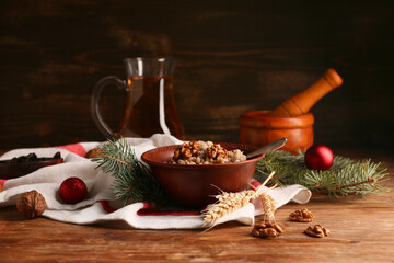 Bowl of traditional Ukrainian Kutya dish with fir branches and Christmas balls on wooden background
