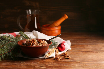 Bowl of traditional Ukrainian Kutya dish with fir branches and Christmas ball on wooden background