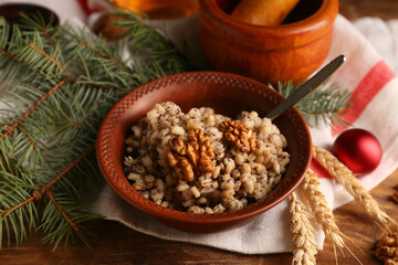 Bowl of traditional Ukrainian Kutya dish with fir branches and Christmas ball on wooden background
