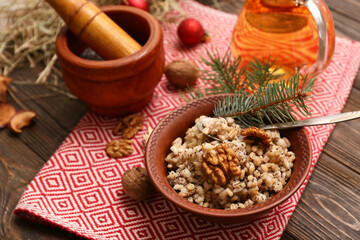 Bowl of traditional Ukrainian Kutya dish with fir branches and jug of uzvar on wooden background