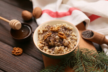 Bowl of traditional Ukrainian Kutya dish with honey and Christmas tree branch on wooden background