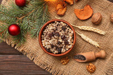 Bowl of traditional Ukrainian Kutya dish with fir branch and Christmas balls on wooden background