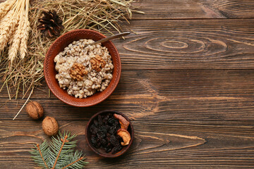 Bowl of traditional Ukrainian Kutya dish with wheat, pine cone and Christmas tree branch on wooden background