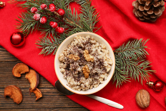 Bowl of traditional Ukrainian Kutya dish with fir branches and Christmas balls on wooden background