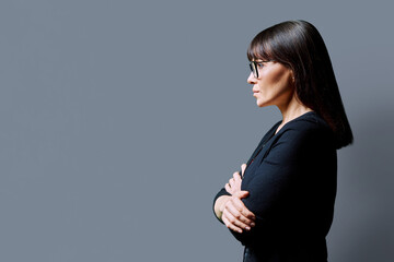 Profile view of serious business woman, gray background, copy space