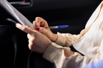 Woman in car dealership signing contract with salesperson after having concerns addressed during test drive. Close up of client completing necessary sale paperwork to buy vehicle after driving it