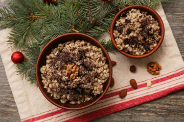 Bowls of traditional Ukrainian Kutya dish with almond nuts and Christmas tree branches on wooden background