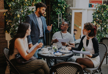 A diverse group of business professionals discussing creative ideas and strategies while meeting outdoors in a modern coffee bar, fostering collaboration and teamwork in a relaxed environment.