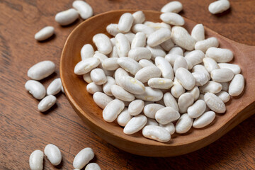 White beans in a spoon on a wooden table
