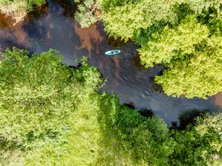 Aerial View of Kayaker on Narrow River Through Dense Forest