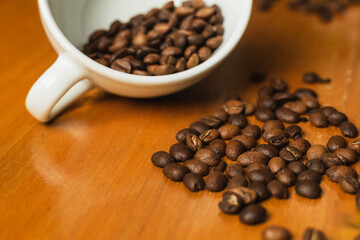 Publicity Day. Colombian coffee. White cup with coffee beans scattered on wooden table with space to copy. Image for advertisement.