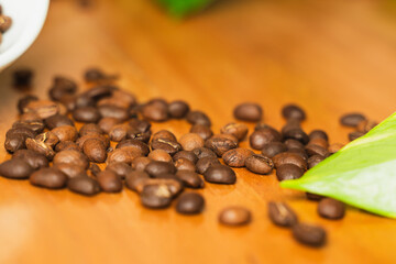 Publicity day. Colombian coffee. White cup with coffee beans sprinkled on wooden table with space for copying. Close-up.