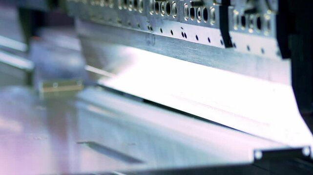A detailed view of a metal sheet being bent by a press brake machine, highlighting the sharp, reflective edge and tooling in an industrial setting.