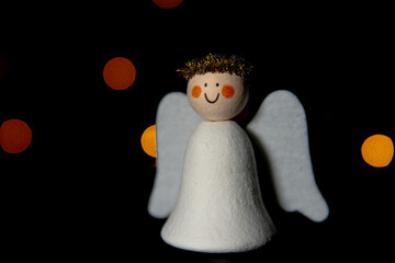 Decorative DIY Christmas Angel figure. Dark background with defocused lights in different colors. Creative Christmas and Easter concept. Right bottom of the frame.