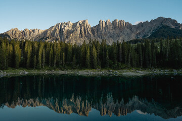 Mountains are reflected in a tranquil lake, surrounded by trees