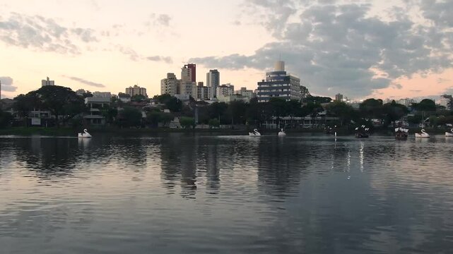 Time lapse of Ipago Lake of Londrina city, Parana, Brazil. Beautiful landscape of the lake at sunset with some pedal boats on the water.