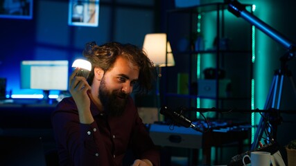 Entertainer using light bulb to create atmospheric mood while entertaining audience. Disheveled man in apartment using light to create spooky vibe, pretending to be electrocuted, camera A