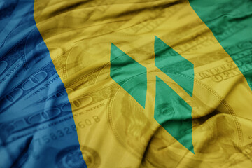 waving colorful flag of saint vincent and the grenadines on the dollar money background. finance...