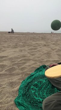 Having fun with friends, bouncing ball over board on the beach a cold cloudy day, Argentina