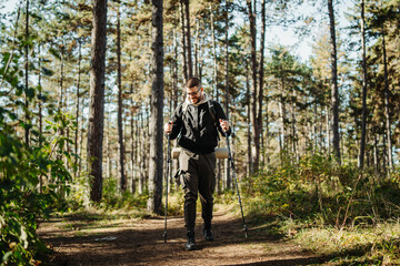 Obraz premium Young caucasian man hiking or trekking through the forest 