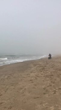 Motorcycle on the beach, riding along the sea, a foggy cloudy gray day, winter in Argentina