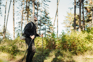 Young caucasian man hiking or trekking through the forest	
