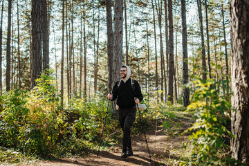Obraz premium Young caucasian man hiking or trekking through the forest 
