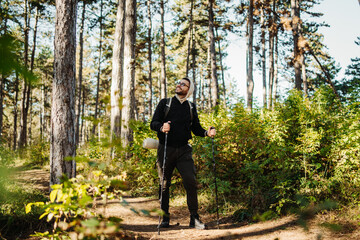 Young caucasian man hiking or trekking through the forest	