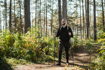 Obraz premium Young caucasian man hiking or trekking through the forest 