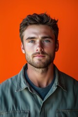 Confident engineer posing on orange background, wearing work uniform