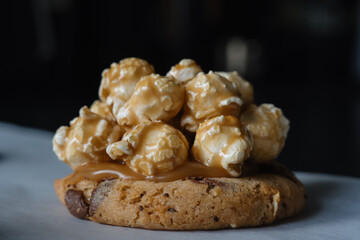 Close up of homemade american traditional chocolate chip cookie with caramel popcorn topping. On black background.