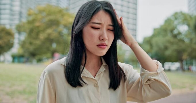 Asian woman, headache and stress with phone at park for fatigue, pain or discomfort in nature. Japanese, female person or migraine with sore ache or mobile smartphone for vertigo in city or town