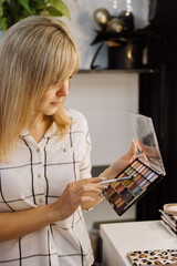 Focused woman choosing colors from a vibrant eyeshadow palette for professional makeup application