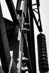 High -voltage transmission lines with a metal rusty mounting with nuts and bolts large plan on a blurred background.