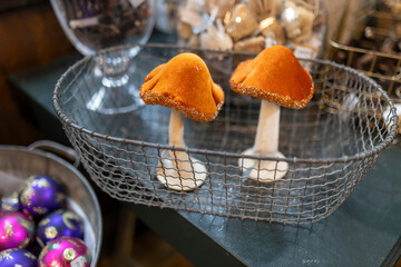 Two sewn fabric mushrooms with orange caps, resembling honey mushrooms, placed in a basket for sale at the market. Christmas decorations.