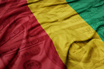 waving colorful flag of guinea on the dollar money background. finance concept.