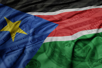 waving colorful flag of south sudan on the dollar money background. finance concept.