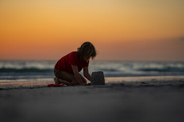 Kid building sandcastle. Kid playing on the beach. Child playing in the sand on tropical beach on...