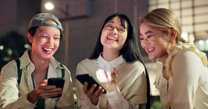 Phone, city friends and students laugh at meme, social media and gif on chat app at night in Japan. College, mobile and Asian people together online, group talking and reading funny joke for comedy