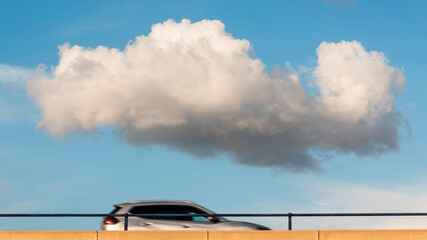 Coche en movimiento por una autopista con una nube en lo alto