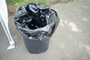 Garbage bucket. Black bag in the bucket. A trash can on the street.