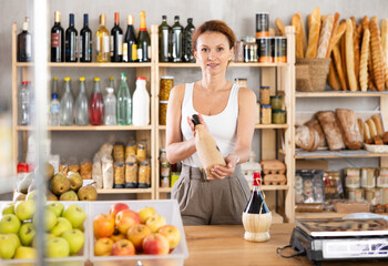 Adult saleswoman offers to buy bottle of wine in grocery store