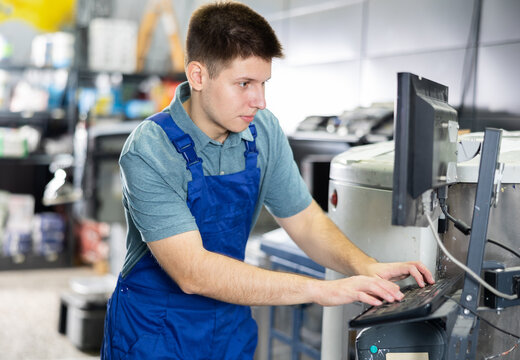 Man worker operating computerised machine to mix paint in big paint shop